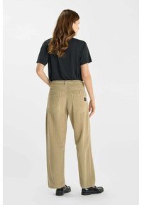 Khaki wijde corduroy broek van een structuurstof, met twee achterzakken en een zwart logo-label. Gecombineerd met een zwart shirt met korte mouwen.