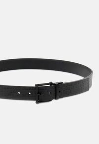 Cintura nera realizzata in materiale testurizzato, con logo "GUESS" impresso, regolabile con una fibbia elegante e multiple perforazioni per la regolazione della misura.