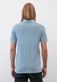 Himmelblaues Polohemd aus weichem Stoff, mit kurzen Ärmeln, einem klassischen Kragen und einem geraden Saum mit seitlichen Schlitzen.