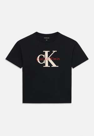 Camiseta negra de manga corta con un gran "cK" beige y el pequeño logo rojo "Calvin Klein" centrados en la parte frontal.