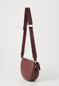 Bordeaux leren schoudertas met een ronde vorm, voorzien van een verstelbare strap, gouden hardware en een gladde textuur.
