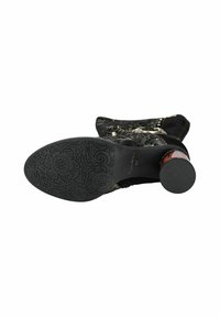 Botte noire au mollet avec semelle emboutie de fleurs, dessus en textile à motifs, bout rond et talon épais et texturé.