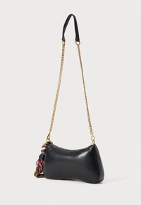 Black leather shoulder bag with a gold chain strap, featuring a zip closure and fabric tassel detail on one side. Smooth texture and curved shape.