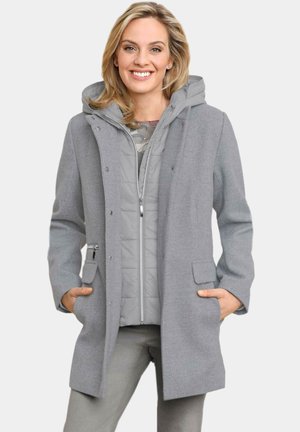 Cappotto grigio intrecciato con motivo a spina di pesce e un sottogonna imbottita removibile. Presenta un cappuccio, tasche frontali e chiusura a scatto.