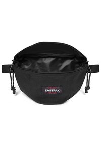 Sort stofpose med rund form, lynlåslukning og en indvendig foring. Har et eksternt Eastpak-logo og snor detaljer.