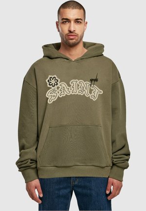 Oliven grønn hettegenser med frontlomme, som har "SAINT" i leken skrifttype og et blomstermotiv. Mykt, teksturert stoff.