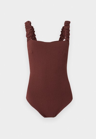 Maillot de bain une pièce marron texturé avec bretelles froncées aux épaules et encolure carrée, présenté sur un fond gris clair uni.