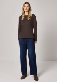 Bruine lange mouwen shirt gecombineerd met wijde blauwe spijkerbroek en bruine enkellaarsjes, met een eenvoudig ontwerp en een ontspannen pasvorm.