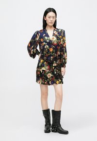 Blommig klänning med puffärmar, svart bas och flerfärgade blommor. Matchas med svarta knähöga stövlar med kedjedetalj.