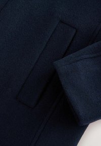 Cappotto in lana navy con una trama liscia, tasca verticale e design delle maniche elegantemente sagomato.
