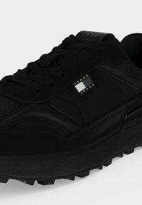 Μαύρο sneaker Tommy Jeans με υφή στη σόλα, δέσιμο με κορδόνια μπροστά και λογότυπο στην πλευρική επιφάνεια και στη γλώσσα.