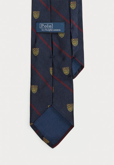 Navy zils kakls ar diagonālām sarkanām svītrām un dzelteniem vairoga emblēmām, ar uzrakstu "Polo by Ralph Lauren".