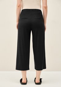Zwarte culottes met een wijd model, elastische tailleband, gladde stof en twee achterzakken. Simpel, ademend en veelzijdig.