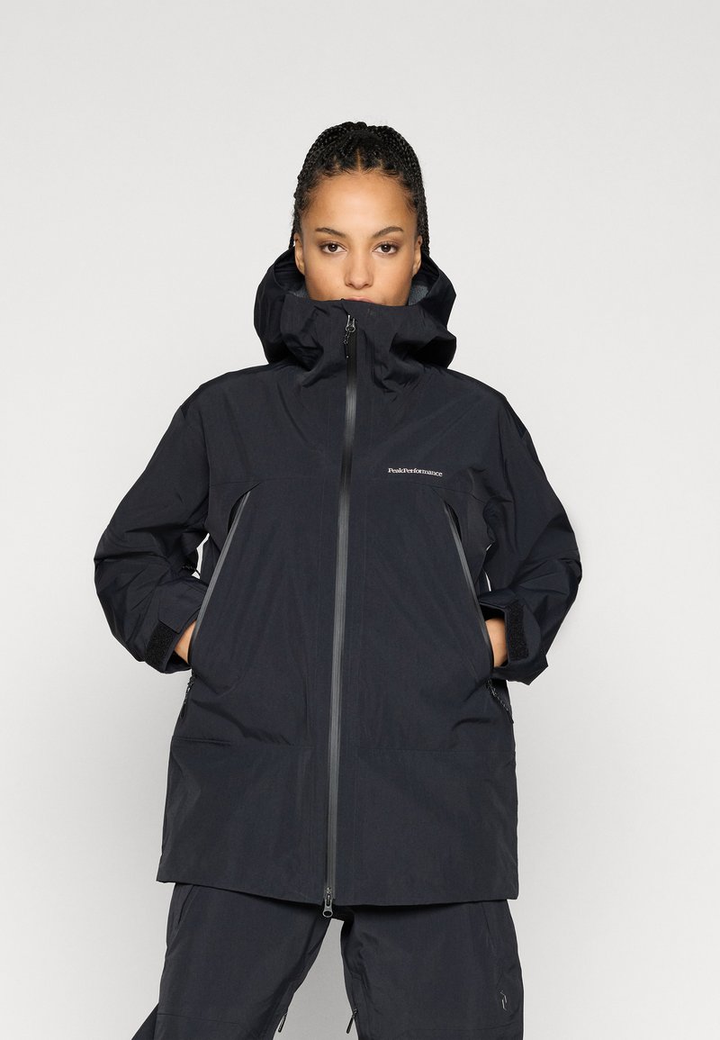 Μαύρο αδιάβροχο μπουφάν με ψηλό γιακά, ρυθμιζόμενη κουκούλα, φερμουάρ και δύο πλευρικές τσέπες. Διαθέτει χαλαρή εφαρμογή και υφασμάτινη υφή.