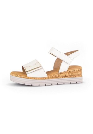 White strap sandal with a cork wedge heel. Features a broad strap with a metallic accent and a textured sole. Lightweight design.