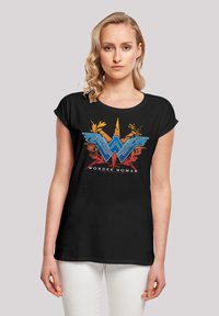 Svart T-skjorte med korte rullete ermer, med et fargerikt Wonder Woman-logo og designelementer i blå, rød, oransje og gul.