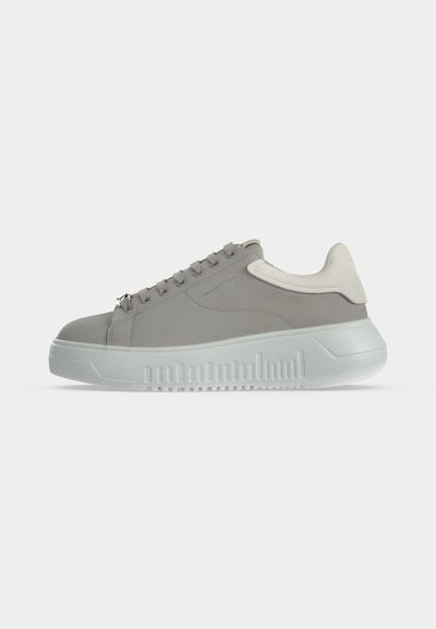 Γκρι sneaker χαμηλού πάτου με λευκή λεπτομέρεια στη φτέρνα και παχύ, υφασμένο λευκό πέλμα σε απλό ανοιχτό φόντο.