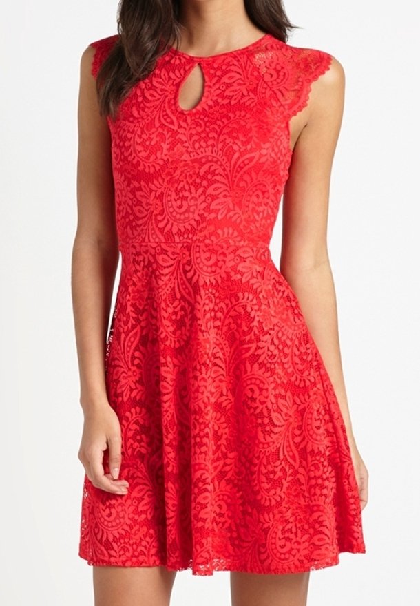 Röd spets, ärmlös klänning med blommönster, nyckelhålshalsringning, figursydd midja och utsvängd kjol, bärs av en stående person.