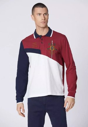 Polo a maniche lunghe caratterizzato da blocchi di colore rossi, bianchi e blu navy, con bottoni, dettagli ricamati e polsini a coste.