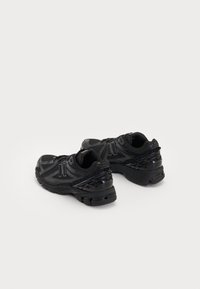 Chaussures de sport noires avec une tige en maille et une semelle en caoutchouc. Caractérisées par des accents texturés et un logo sur le côté. Lacets pour un maintien sécurisé.