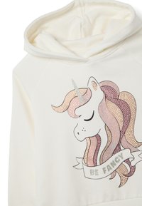 Crème kleurige hoodie met een eenhoornontwerp, voorzien van metalen accenten en een banner met "Be Fancy", gedetailleerd met iriserende texturen en kleuren.