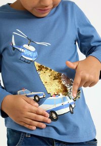 Blå langærmet skjorte med grafik af en helikopter og en politibil, prydet med guld palietter på brystet, blødt bomuldsmateriale, afslappet pasform.