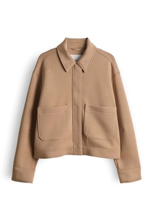 Giacca beige corta con scollo a collo, caratterizzata da due grandi tasche frontali e una trama liscia. Design a taglio dritto con dettagli di cuciture.