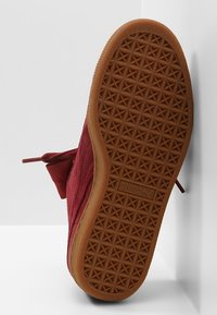 Semelle d'une basket Puma en daim marron avec une semelle en caoutchouc marron présentant des motifs de bande de roulement triangulaires et le logo Puma au centre.