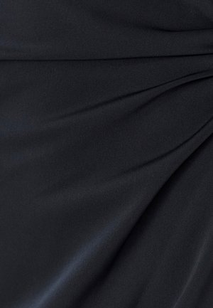 Tissu noir à texture lisse, présentant un drapé doux et des plis, créant un léger éclat sur toute la surface.