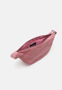 Růžová kabelka z manšestru se zipem, s hladou vnitřní podšívkou a zavázaným držadlem. Na vnějšku má žebrovanou texturu.