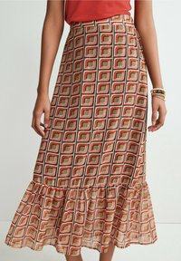 Jupe midi multicolore avec un motif géométrique en rouge, orange et marron. Dotée d'un ourlet à volants évasé et d'une taille ajustée.