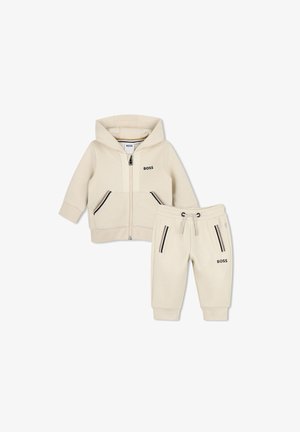 Sweat à capuche pour tout-petit couleur crème avec joggings assortis, fermeture éclair à l'avant et poches, marqué "BOSS" sur la poitrine et la jambe.