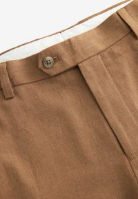 Brązowe lekkie spodnie wykonane z teksturowanej tkaniny, z zapięciem na guzik i gładkim przodem. Wewnątrz mają kontrastową, białą podszewkę.