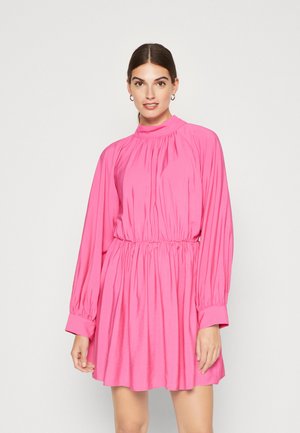 Robe rose à manches longues avec un col montant, une taille élastique et un tissu froncé. Texture lisse et coupe ample, se terminant au-dessus du genou.