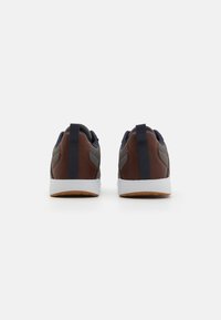 Sports shoes with a dark blue and brown leather upper, textured accents, white outsole, and brown rubber sole. Features rear pull tab.