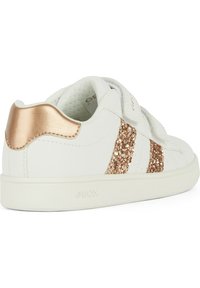 Baskets blanches avec des accents dorés roses, présentant des rayures pailletées et une fermeture velcro. Fabriquées en matériau synthétique lisse.