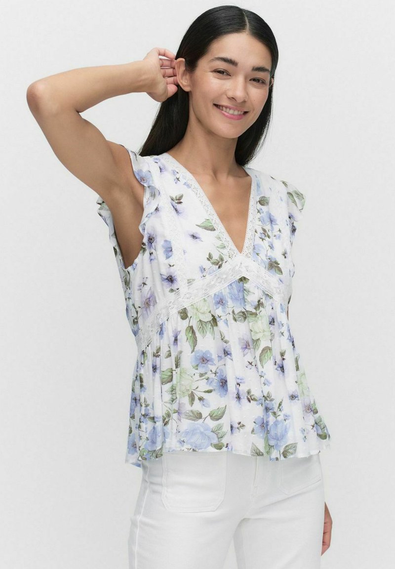 Ärmellose Bluse mit floralem Muster, Rüschen an den Schultern, V-Ausschnitt und Spitzenrand. Sie zeigt hellblaue und grüne Blumen auf einem weißen Hintergrund.