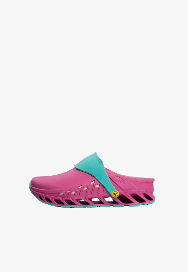 Pinkfarbener, belüfteter Slip-On-Clog mit verstellbarem türkisfarbenem Riemen und Sohle, mit einer strukturierten Fußbettung und einem gelben Logo-Knopf an der Seite.