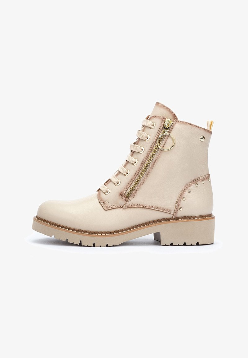 Botas de tobillo beige de cuero, con cremallera frontal, diseño con cordones, detalles de tachuelas en el tacón y suela de bloque.