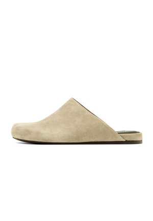 Beige Wildleder-Pantoffel mit geschlossenem, abgerundetem Zehenbereich und flacher schwarzer Sohle, seitlich auf weißem Hintergrund dargestellt.