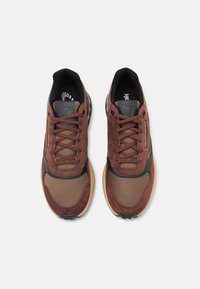 Bruna mocka och mesh-sneakers med svarta accenter, rund tå och flätade skosnören. Har texturerade sulor och diskret branding på tungan.