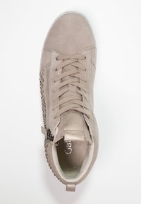 Beige mockasins höga sneakers med rund tå, snörning framtill, metalliska detaljer, sidodragkedja och dekorativt nitar design på överdelen.