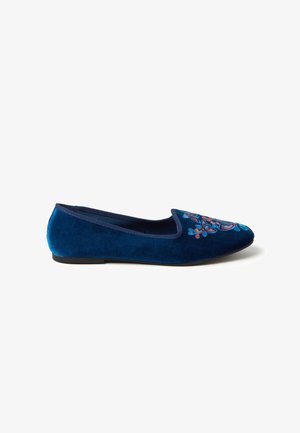 Blue velvet flat shoe with embroidered colorful floral design on the toe and a black sole, shown in side profile on white background.