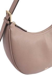 Sac à épaule en cuir beige clair de forme arrondie, avec quincaillerie dorée et une fermeture éclair en haut. Fini lisse et texturé avec une sangle réglable.