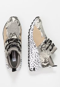 Baskets au design en matériaux mixtes avec un motif peau de serpent en gris et noir, des accents beige et une semelle blanche mouchetée. Lacets noirs.