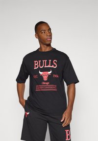 Sort T-shirt med korte ærmer, der har rød tekst og logo "BULLS", med "EST. 1966" og "EASTERN CONFERENCE" trykt nedenfor. Casual pasform.