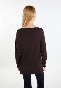 Brauner oversize Pullover mit weit ausgeschnittenem Rundhalsausschnitt, langen Ärmeln und geripptem Saum. Glatte Textur, gerader Schnitt und dezente Nahtdetails.