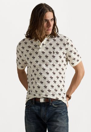 Polo à manches courtes en crème avec un motif répétitif de chevaux et de cavaliers. Doté d'une patte de boutonnage à deux boutons et d'un tissu texturé.