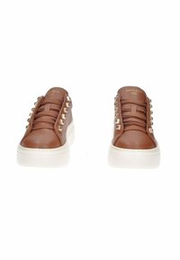 Sneaker in pelle marrone con texture, suola in gomma bianca, caratterizzati da borchie metalliche lungo i lati e lacci piatti per la chiusura.