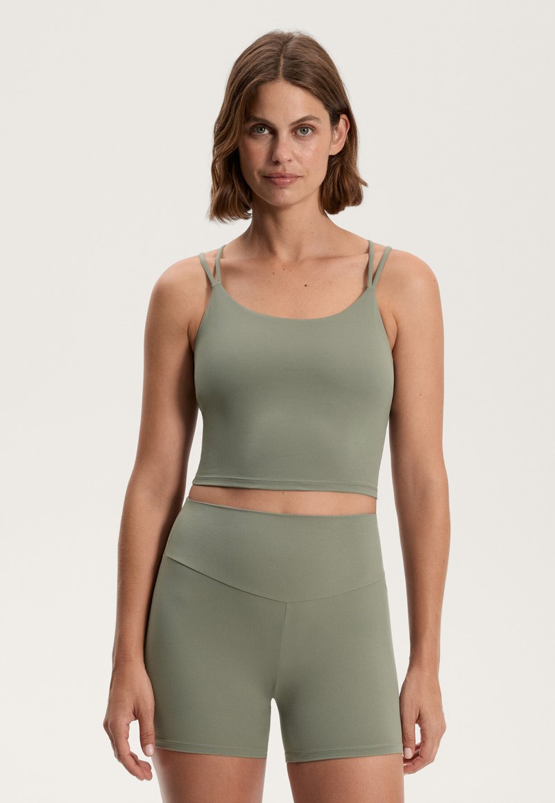 Világoszöld sportöltözet, amely egy vékony pánttal rendelkező cropped tank topból és sima, rugalmas anyagú, magas derekú sortból áll.